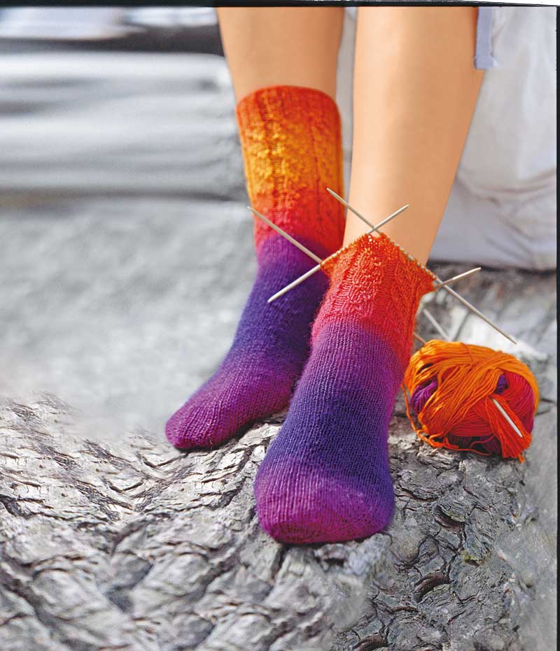 Selbstgemachte Socken in lebhaftem Rot-Orange-Lila-Verlauf. DIY, handgestrickt, warmes Farbspiel.