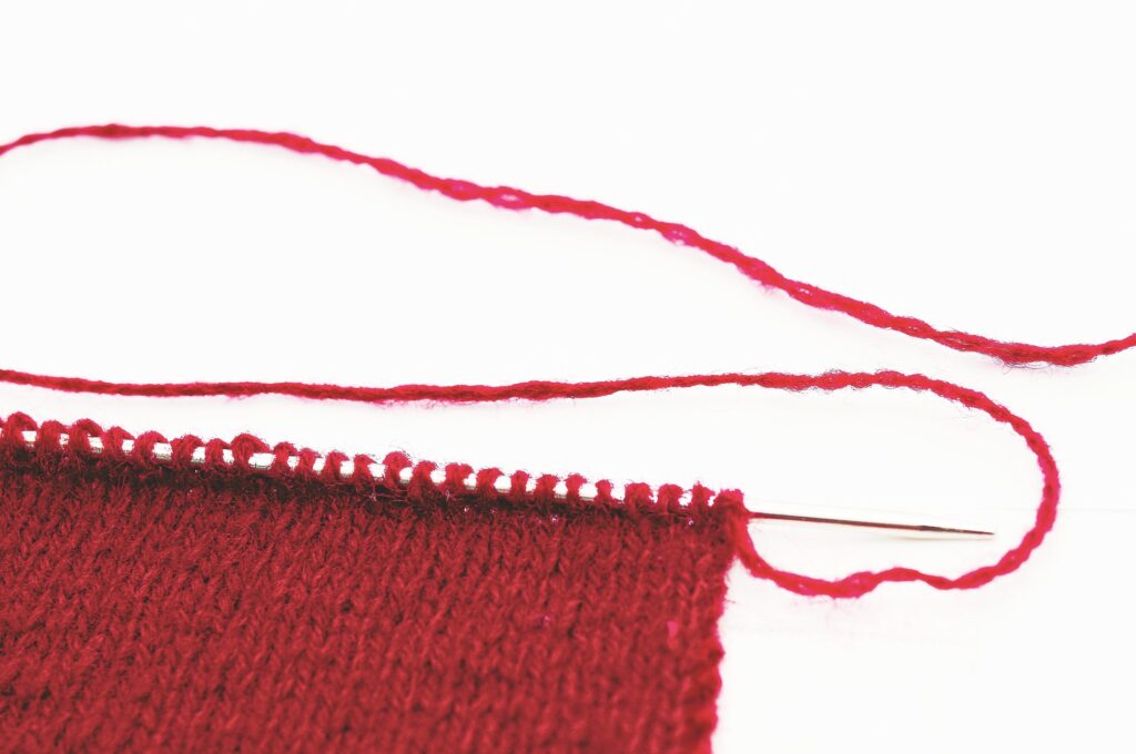 Handgemachte, rote Strickarbeit aus feiner Wolle. DIY-Muster, elegant und schlicht.